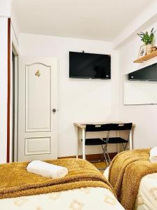 Habitación blanca con 2 camas y escritorio. en Alojamiento Calma, en Hospitalet de Llobregat