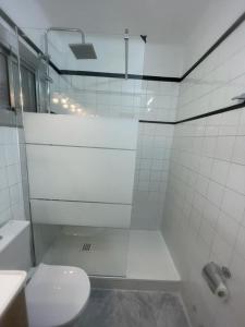 a white bathroom with a toilet and a shower at Alojamiento Calma in Hospitalet de Llobregat +13 photos