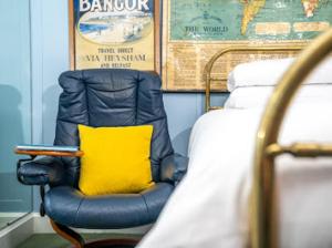 una silla con una almohada amarilla junto a una cama en Cairn Bay Lodge en Bangor