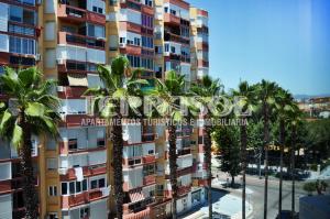 un edificio alto con palmeras delante en Apartamentos Terrasol Plazamar, en Torre del Mar