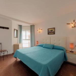 1 dormitorio con 1 cama grande y edredón azul en Apartamentos Terrasol Plazamar, en Torre del Mar
