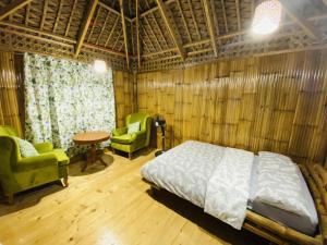 a bedroom with a bed and two chairs and a table at Birbeck Lodge in Bulusan