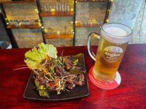 a plate of food and a glass of beer on a table at Khmer Cozy in Battambang