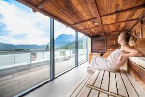 a woman sitting on a bench in a room with windows at MyTirol in Biberwier