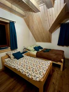 two beds in a room with a attic at Domek Między Górami in Łapsze Niżne