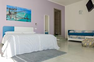 a white bedroom with a bed and a painting on the wall at Villa Caravaggio Comfort e Relax in Rocca San Giovanni