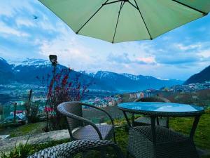 tavolo e sedie con ombrellone e vista sulla città di Himalayan Village Resort, Manali a Manāli