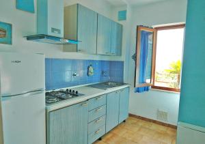a kitchen with blue cabinets and a white refrigerator at Arlecchino in Capoliveri