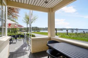 a porch with tables and chairs and a view of the water at Skovdal Kro in Jelling