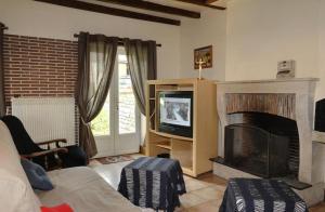 ein Wohnzimmer mit einem Kamin und einem TV in der Unterkunft Le four banal in Bligny
