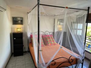 a bed with a canopy in a room with a window at MARINA DU MARIN in Le Marin