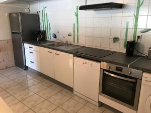 a kitchen with white cabinets and a black refrigerator at MARINA DU MARIN in Le Marin