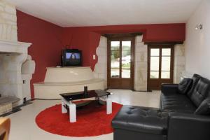 ein Wohnzimmer mit einem schwarzen Sofa und einem TV in der Unterkunft Les perrieres in Les Riceys