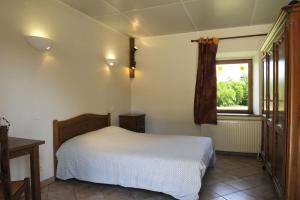 1 dormitorio con cama blanca y ventana en Le cellier aux moines, en Colombé-le-Sec