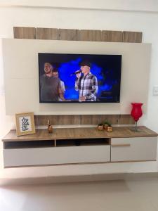 a flat screen tv on a wall in a living room at Ap em barra grande c/ piscina in Marau