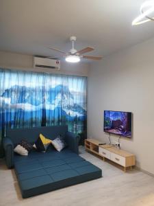 sala de estar con sofá azul y TV en JQ Citypads by Golden Stay en Kota Kinabalu
