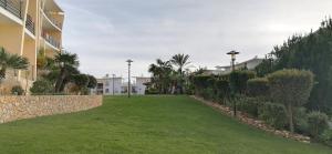 a grassy yard next to a building with palm trees at Encosta Da Orada in Albufeira