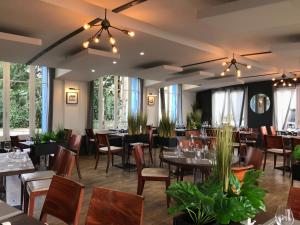 a dining room with tables and chairs and windows at LOGIS Hôtel & Restaurant - Les Bords de Seine in La Roche-Guyon