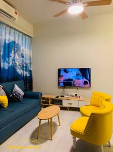 un salon avec un canapé bleu et un fauteuil jaune dans l'établissement JQ Citypads by Golden Stay, à Kota Kinabalu