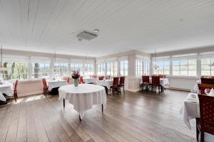 a dining room with white tables and chairs and windows at Skovdal Kro in Jelling