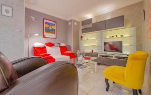 a living room with red and yellow chairs and a television at Le gros raisin in Troyes