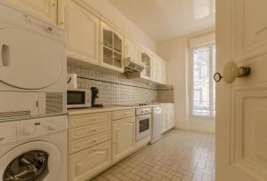a kitchen with white cabinets and a washer and dryer at L'alnilia in Romilly-sur-Seine