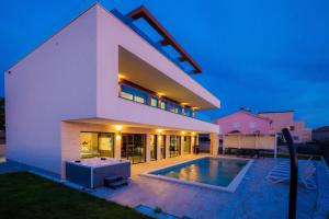 a large white house with a swimming pool at Luxury Villa Eligo with private pool and sea view in Premantura