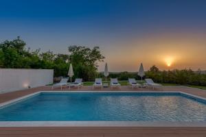 a swimming pool with lounge chairs and a sunset at Luxury Villa Eleven near Rovinj for 10 persons only 4 km from the Beach in Rovinjsko Selo