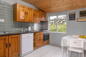 eine Küche mit Holzschränken, einem Tisch und einem Fenster in der Unterkunft Into The Burren in Murroogh