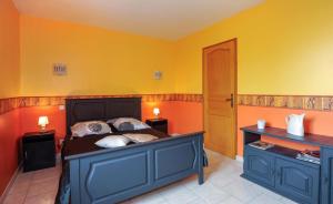 Schlafzimmer mit einem Bett mit gelben und orangefarbenen Wänden in der Unterkunft Les fretees in Laines-aux-Bois