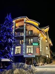 a christmas tree in front of a building with lights at Sadyba u Halyny in Bukovel