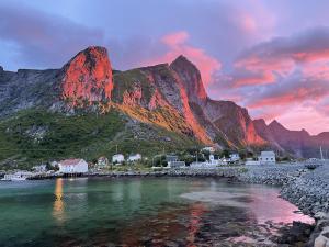 a mountain with a red light on it next to the water at #Reinehuset - Amazing view! in Reine