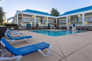 a resort with a swimming pool and blue lounge chairs at Baymont by Wyndham Camp Lejeune in Jacksonville