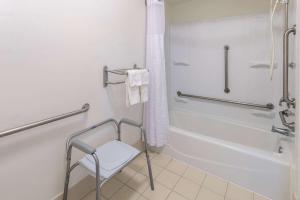 een badkamer met een douche en een stoel. bij Studio 6 Suites Jacksonville, NC in Jacksonville