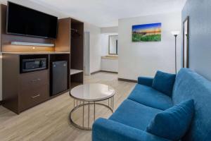 a living room with a blue couch and a tv at Baymont by Wyndham Camp Lejeune in Jacksonville