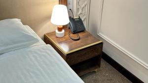 a lamp on a table next to a bed and a phone at Reikartz Sote Tashkent in Tashkent