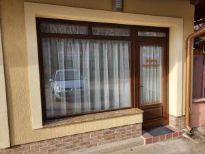 une porte en verre avec une voiture dans la fenêtre dans l'établissement Glória Apartman Szarvas, à Szarvas