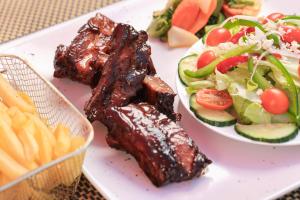 a plate of food with ribs and a salad at Green Lagoon Guest House Tawana in Gaborone