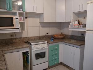 a kitchen with white cabinets and a stove top oven at Hostel Casa Mineira in Belo Horizonte