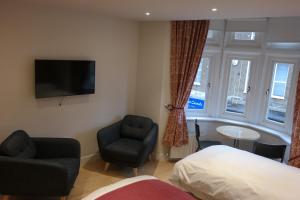 a bedroom with a bed and a chair and a television at The Alma Rooms in London