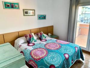 ein Schlafzimmer mit einem Bett mit einer bunten Decke und Kissen in der Unterkunft Paz y desconexión in Denia