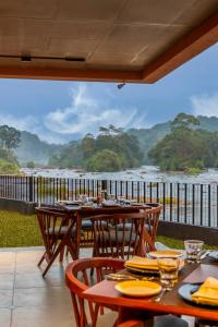 een patio met tafels en stoelen en uitzicht op een rivier bij Sterling Athirappilly in Kallana