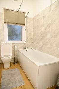 ein Badezimmer mit einer weißen Badewanne und einem WC in der Unterkunft Aqua Springs, luxury 2 bed, 2 bath apartment, near Didsbury in Manchester