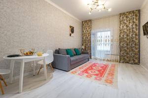 een woonkamer met een bank en een tafel bij Комфортабельная квартира в ЖК Apple City in Astana