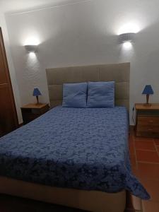 a bedroom with a bed with blue sheets and blue pillows at Monte das Galhanas in Monte do Pigeiro