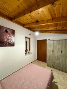 a bedroom with a pink bed and a wooden ceiling at Alleyhouse 83 in Kremasti