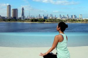 une femme assise sur la plage et vue sur la ville dans l'établissement Park Hyatt Dubai, à Dubaï