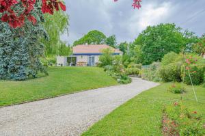 um jardim com uma casa e uma entrada de cascalho em La maison vautier em Vendeuvre-sur-Barse