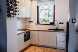 uma cozinha com armários brancos, uma janela e um lavatório em Rezydencja Park OB7 em Mielno