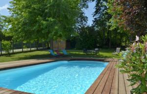 a swimming pool with a wooden deck and a yard at La maison vautier in Vendeuvre-sur-Barse